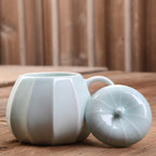 Celadon ceramic pumpkin mug on a wooden table
