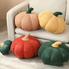 Plush pumpkin pillows in blush, butter, rust and forest green on a sofa