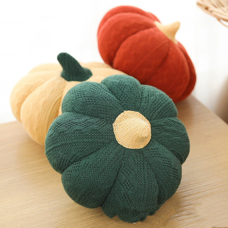 Forest green, rust and butter plush pumpkin pillows on a wooden table
