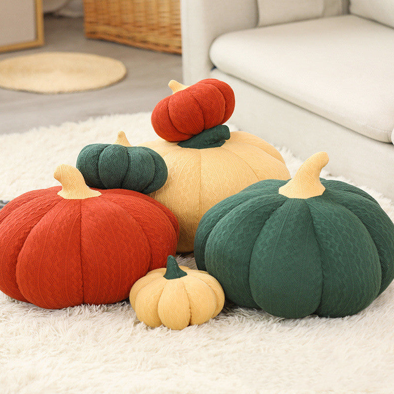Plush pumpkin pillows in four colours arranged on a living room rug